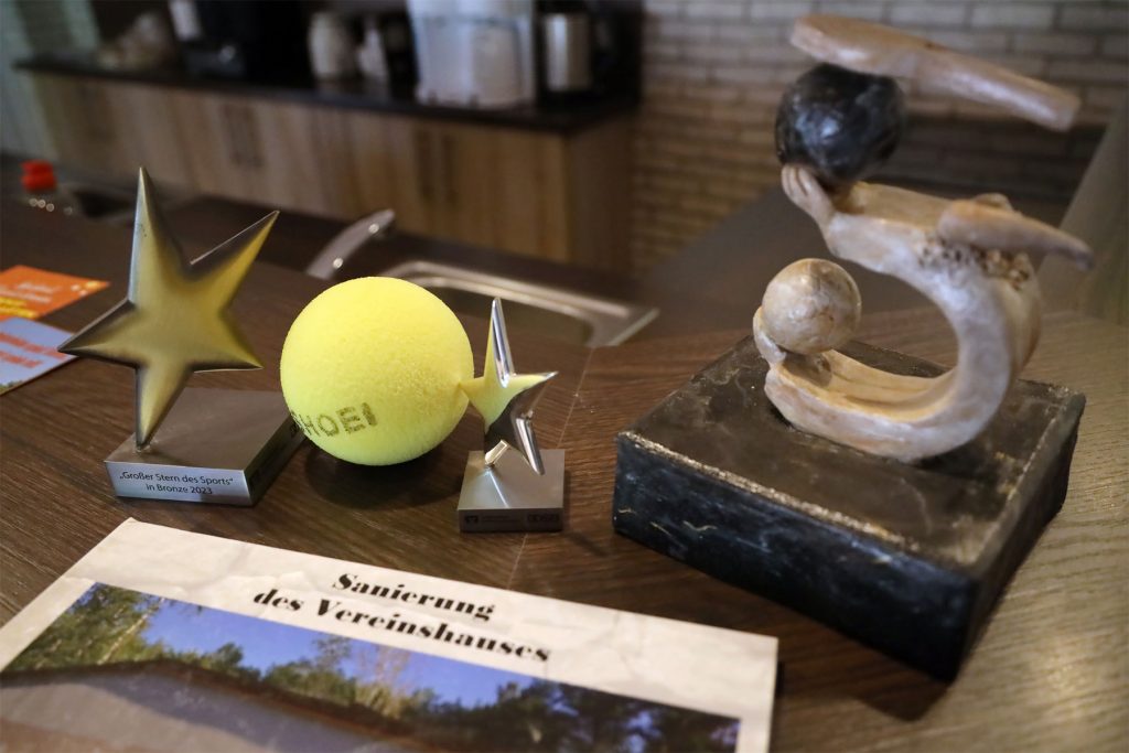 Blinen-Tennisball zwischen Trophäen des Vereins